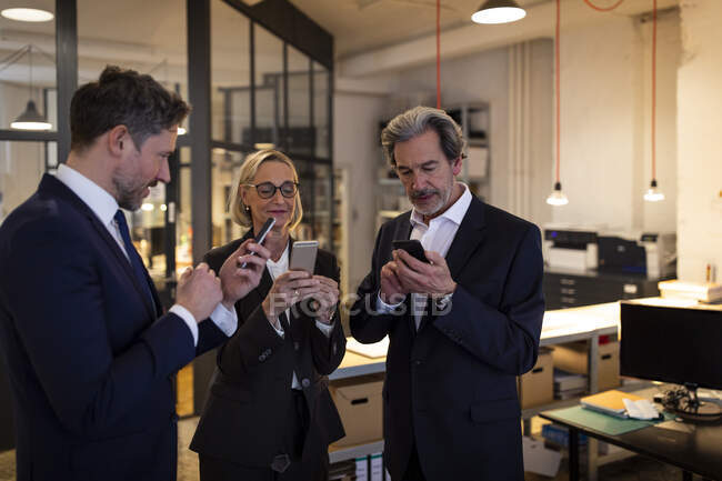 Gente de negocios usando teléfonos inteligentes en la oficina - foto de stock