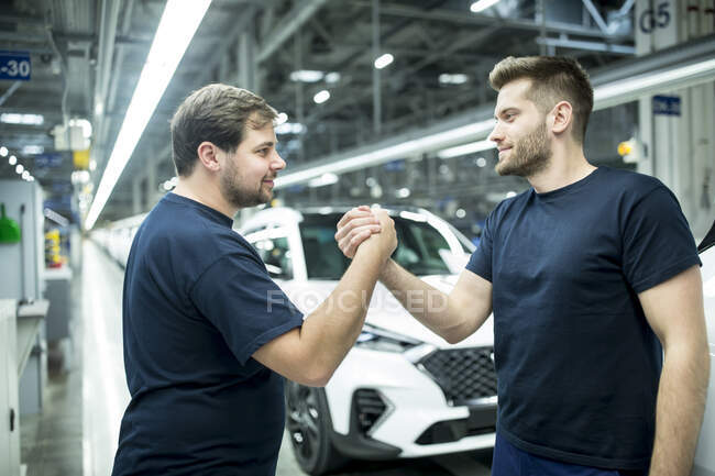 Due colleghi che stringono la mano nella moderna fabbrica di automobili — Foto stock