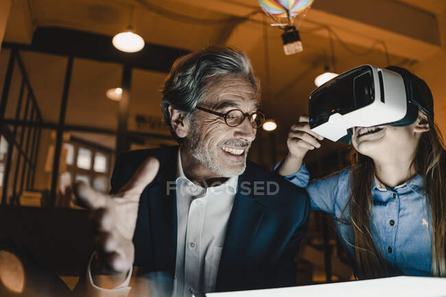 Buisinessman sênior feliz e menina vestindo óculos VR com balão de ar quente no escritório — Fotografia de Stock