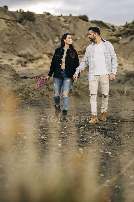 Молода пара йде рука в руку через пустинний краєвид, Альмерія, Андалусія, Іспанія. — стокове фото