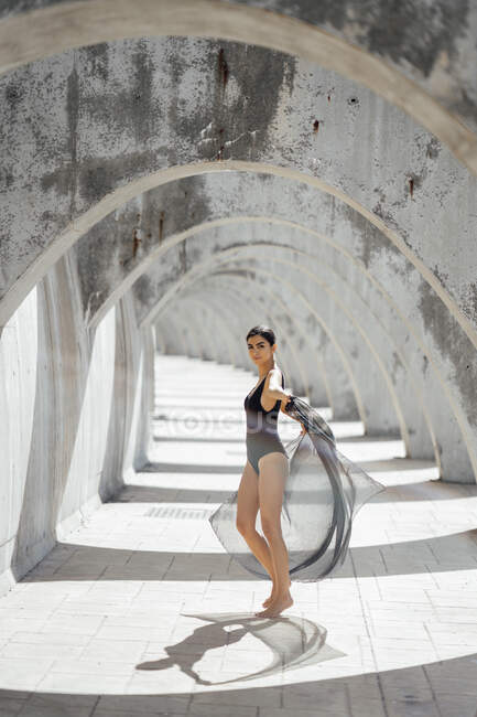 Young woman wearing black swimsuit dancing in an archway — Stock Photo