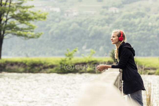 Jeune femme avec casque rouge relaxant au Lac Idro, Baitoni, Italie — Photo de stock