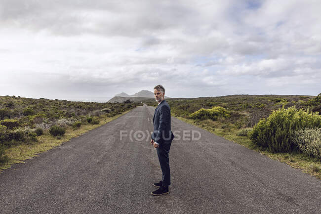 Homme d'affaires debout sur la route de campagne, Cape Point, Western Cape, Afrique du Sud — Photo de stock