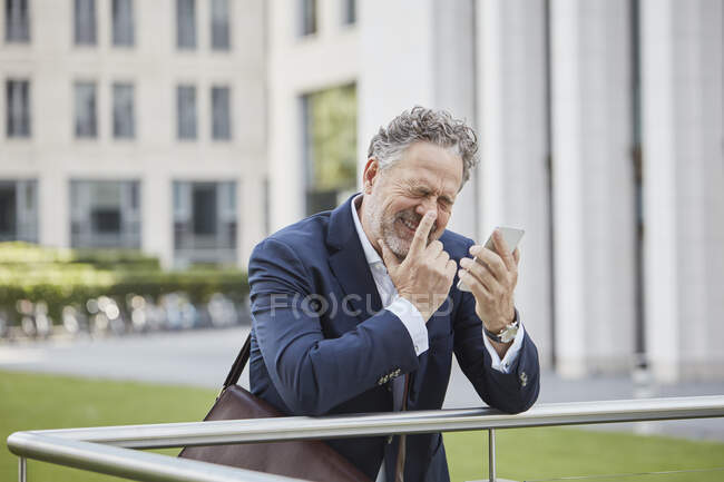 Happy mature businessman with smartphone in the city — Stock Photo