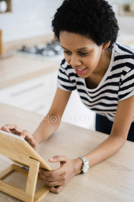 Mujer joven usando la tableta en la cocina en casa - foto de stock