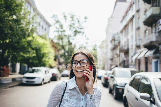 Glückliche junge Geschäftsfrau telefoniert auf der Straße — Stockfoto