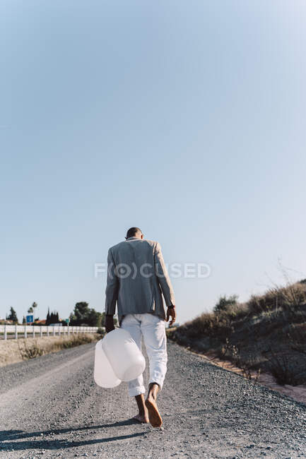 Молодой человек держит пустые банки с водой, идущие по грунтовой дорожке — стоковое фото