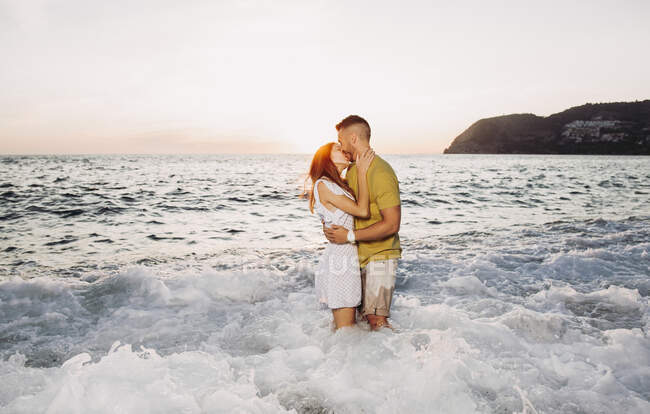Giovane coppia baciarsi in spiaggia durante il tramonto — Foto stock