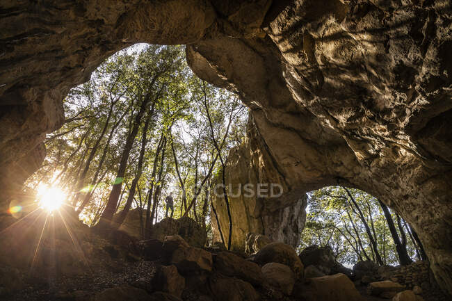 Женщина на выходе из пещеры в подсветке, Финал Лигуре, Лигурия, Италия — стоковое фото