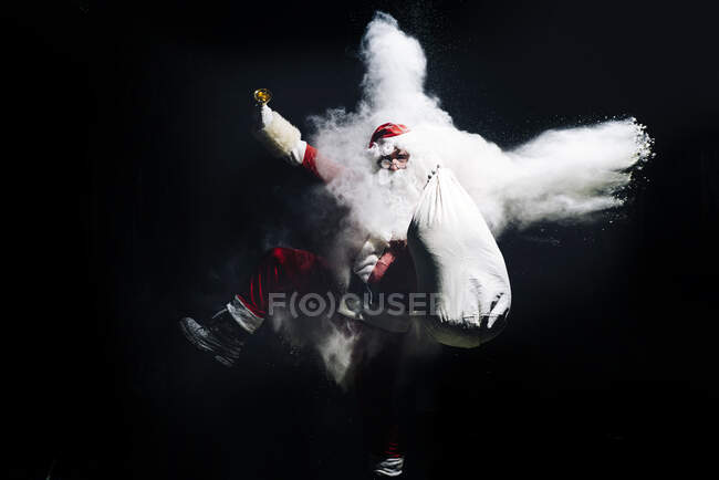 Санта Клаус вибухає сніговою бомбою на чорному тлі. — стокове фото