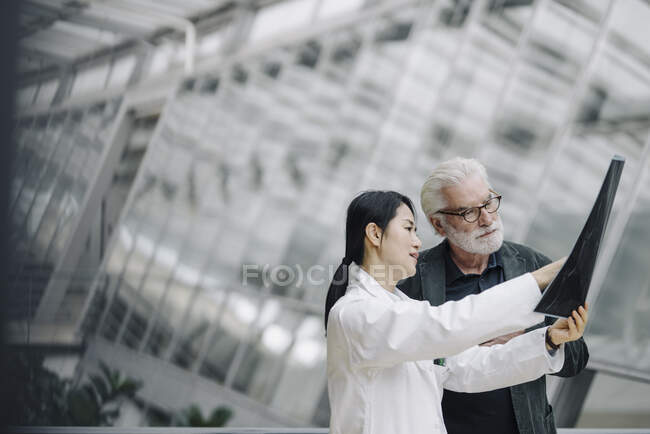 Female doctor discussing x-ray with senior patient — Stock Photo
