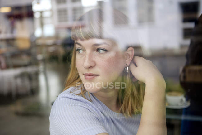 Портрет молодой женщины в кафе, выглядывающей в окно — стоковое фото