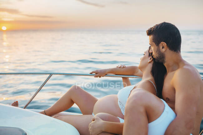 Романтична пара з вагітною жінкою сидить на човні. — стокове фото
