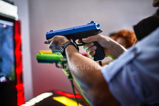 Close-up de amigos brincando e atirando com pistolas em uma arcada de diversão — Fotografia de Stock