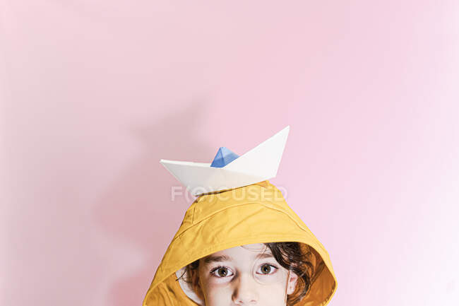 Bambina che indossa una pelle d'olio e porta una barca di carta sulla testa — Foto stock