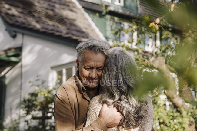 Senior man hugging his wife in garden of their home in autumn — Stock Photo