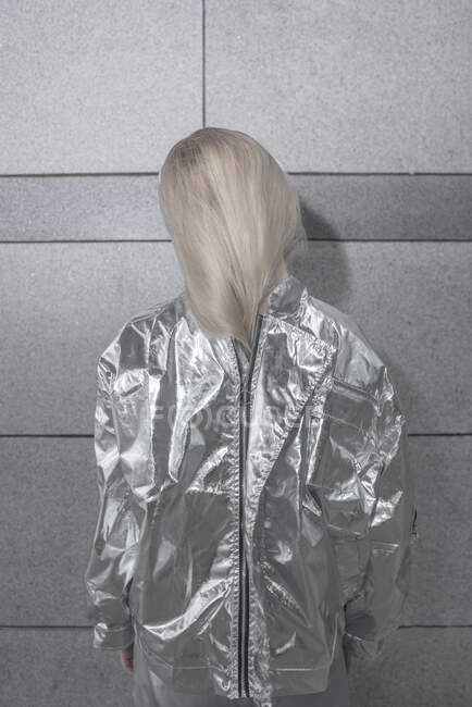 Rückansicht eines Mädchens im silbernen Anzug vor grauer Wand — Stockfoto