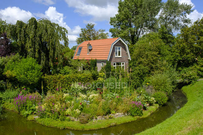 Pays-Bas, Hollande-Septentrionale, Hoorn, fossé du lac Ijssel s'étendant devant le jardin fleuri de la maison rustique — Photo de stock