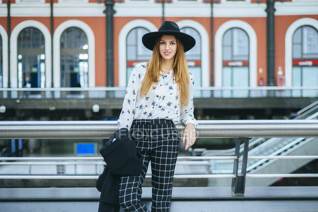 Portrait d'une jeune femme souriante portant un chapeau à la gare — Photo de stock