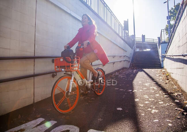 Jovem mulher andando pela cidade em uma bicicleta de aluguel — Fotografia de Stock