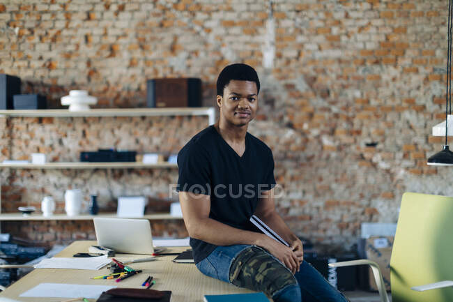 Portrait d'un jeune homme confiant à table au bureau — Photo de stock