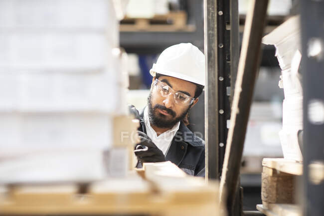 Giovane uomo con un cappello duro che lavora in un magazzino — Foto stock
