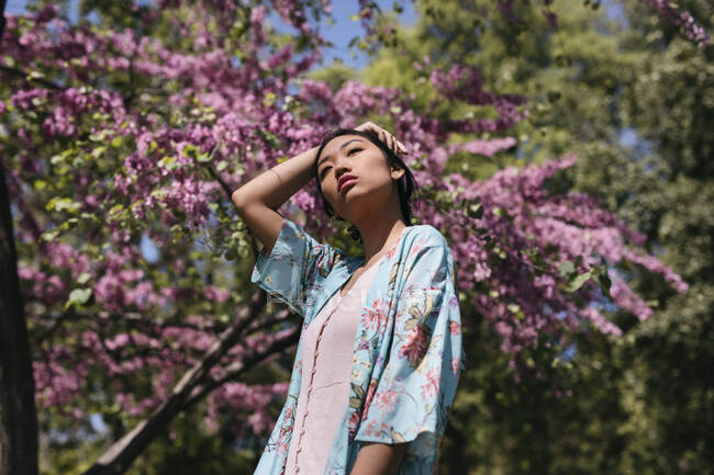 Hermosa mujer joven con cerezo en flor en un jardín público en primavera - foto de stock