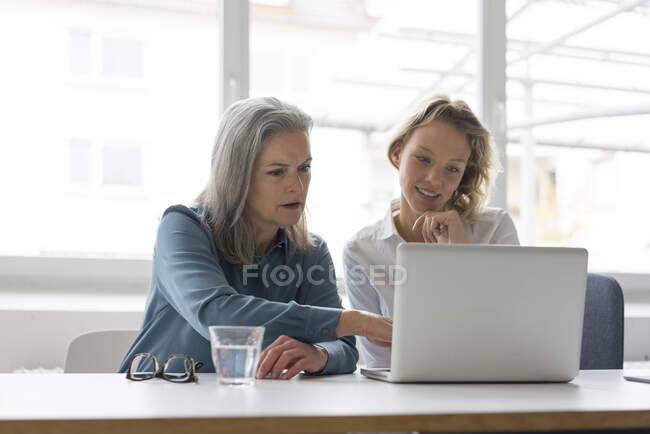 Deux femmes d'affaires utilisant un ordinateur portable au bureau ensemble — Photo de stock