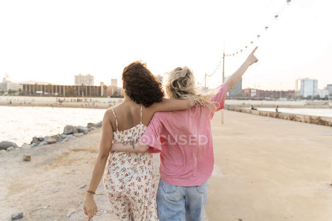Rear view of two young women on waterfront promenade at sunset — Stock Photo