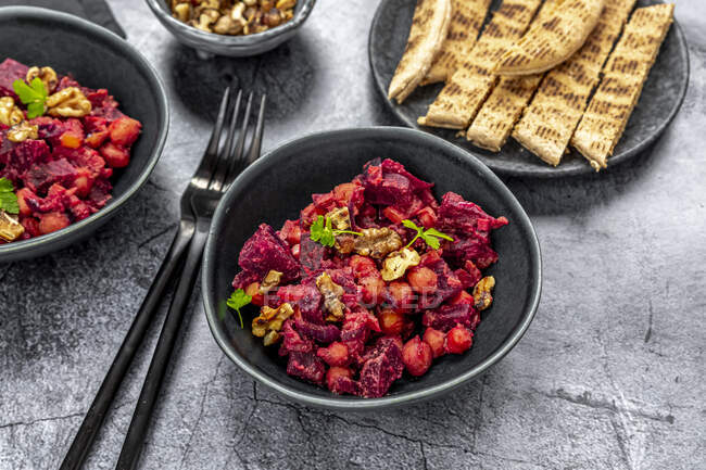Pita bread and plates of beetroot salad with chick-peas, roasted walnuts and parsley — Stock Photo