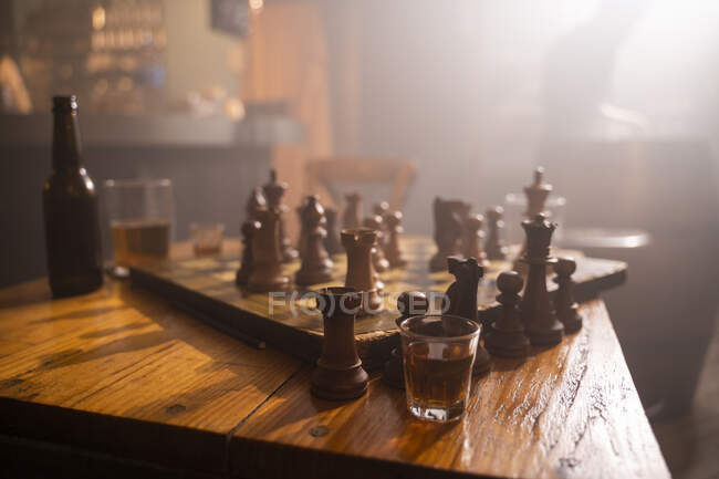 Old wooden chess board and drink on table in a pub — Stock Photo