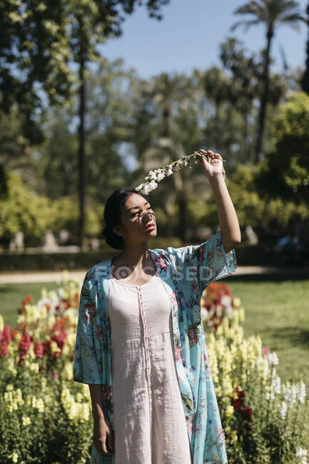 Beautiful young woman holding flower in a public garden in spring — Stock Photo
