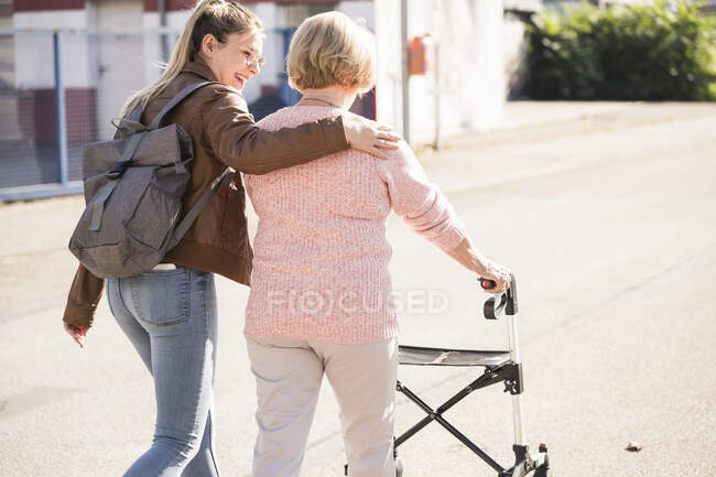 Внучка помогает бабушке с ходунком на колесах. — стоковое фото