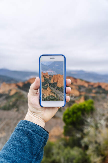 Hombre sosteniendo smartphone con foto de Mina de Oro Romana, Las Medulas, Castilla y León, España - foto de stock
