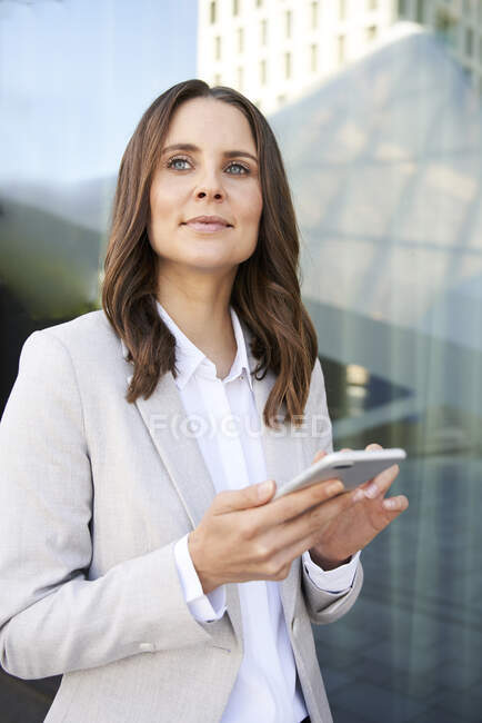 Retrato de empresaria confiada con teléfono celular en la ciudad - foto de stock