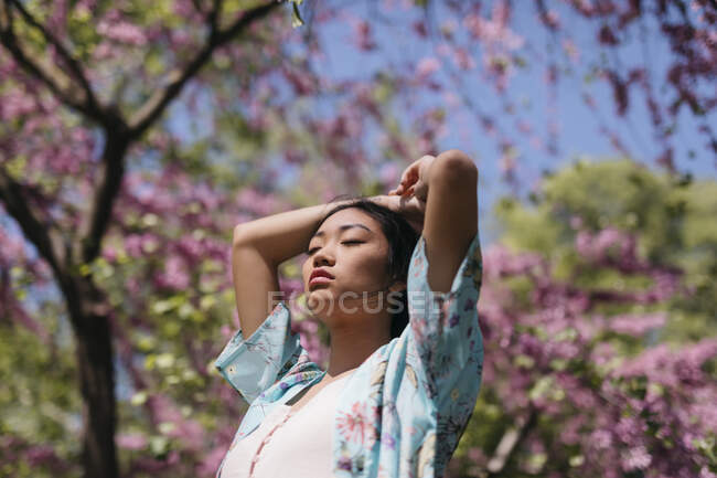 Mulher bonita com árvore de cereja florescendo em um jardim público na primavera — Fotografia de Stock