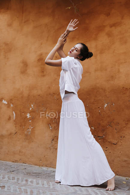 Portrait of female teenager wearing white clothes in front of a brown wall — Photo de stock