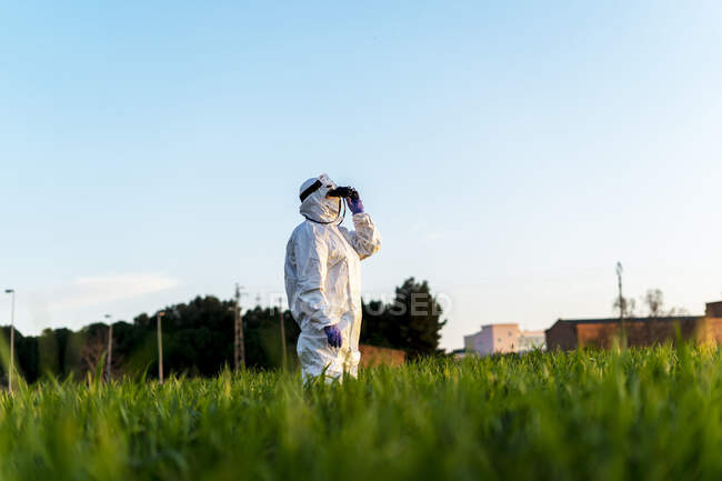 Científica investigando en el campo y mirando a través de binoculares al atardecer - foto de stock