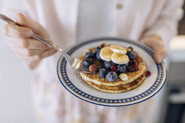 Close-up of woman holding a plate with pancakes and fruit — Stock Photo