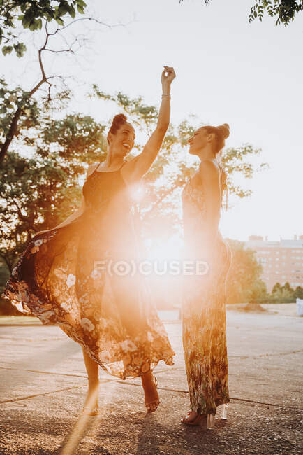 Duas irmãs gêmeas alegres dançando ao ar livre ao pôr do sol — Fotografia de Stock
