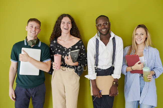 Portrait of happy casual colleagues standing together in front of a green wall — Stock Photo