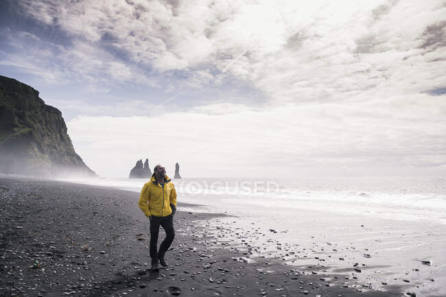 Hombre maduro caminando en una playa de lava en Islandia - foto de stock