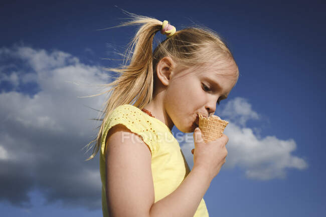 Retrato de menina loira comendo sorvete contra o céu — Fotografia de Stock
