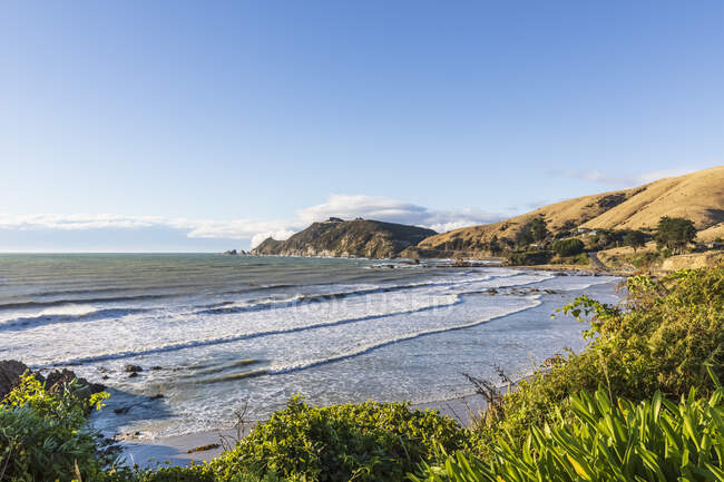 Новая Зеландия, Небо над волнами чистит прибрежный пляж Nugget Point — стоковое фото