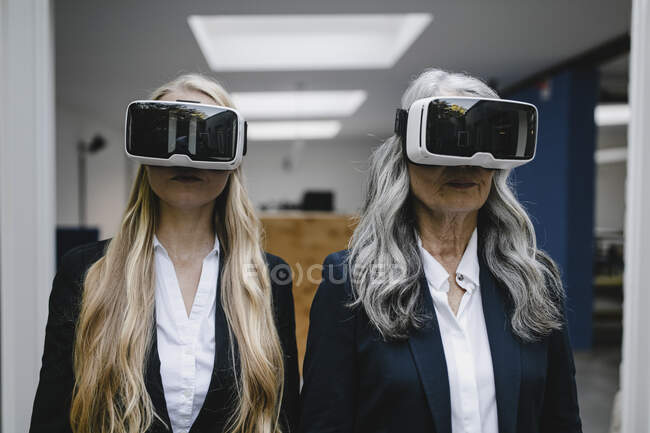 Mature and young businesswoman wearing VR glasses — Stock Photo