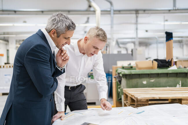 Dois empresários discutindo papel em uma fábrica — Fotografia de Stock