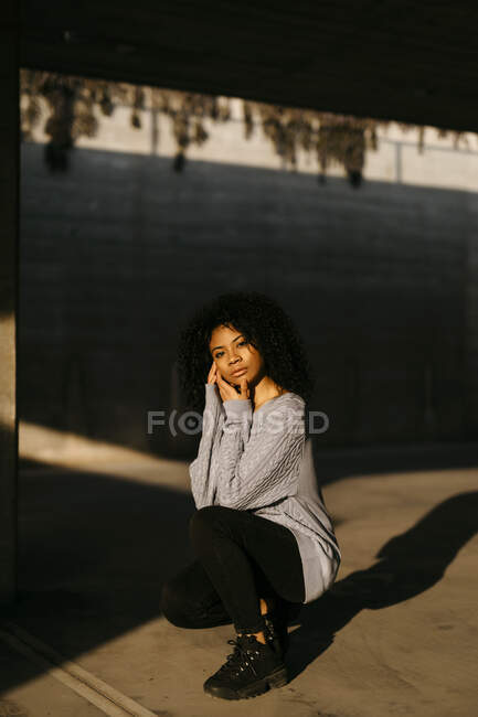 Portrait of a beautiful young woman crouching in sunlight — Stock Photo