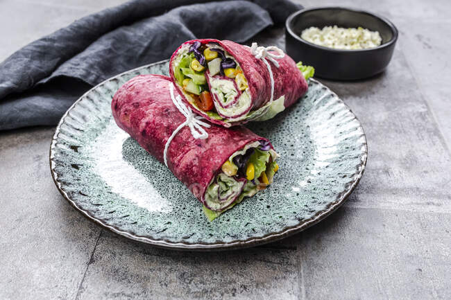 Vegetarian beetroot wraps filled with tomatoes, red cabbage, corn, iceberg lettuce, cucumbers and cream cheese — Stock Photo