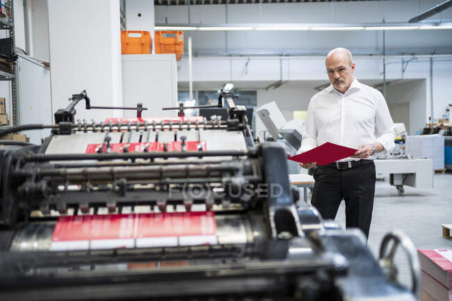 Businessman in a printing plant checking product — Stock Photo