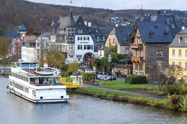 Alemania, Renania-Palatinado, Traben-Trarbach, Ferry amarrado frente a las casas de la ciudad ribereña - foto de stock